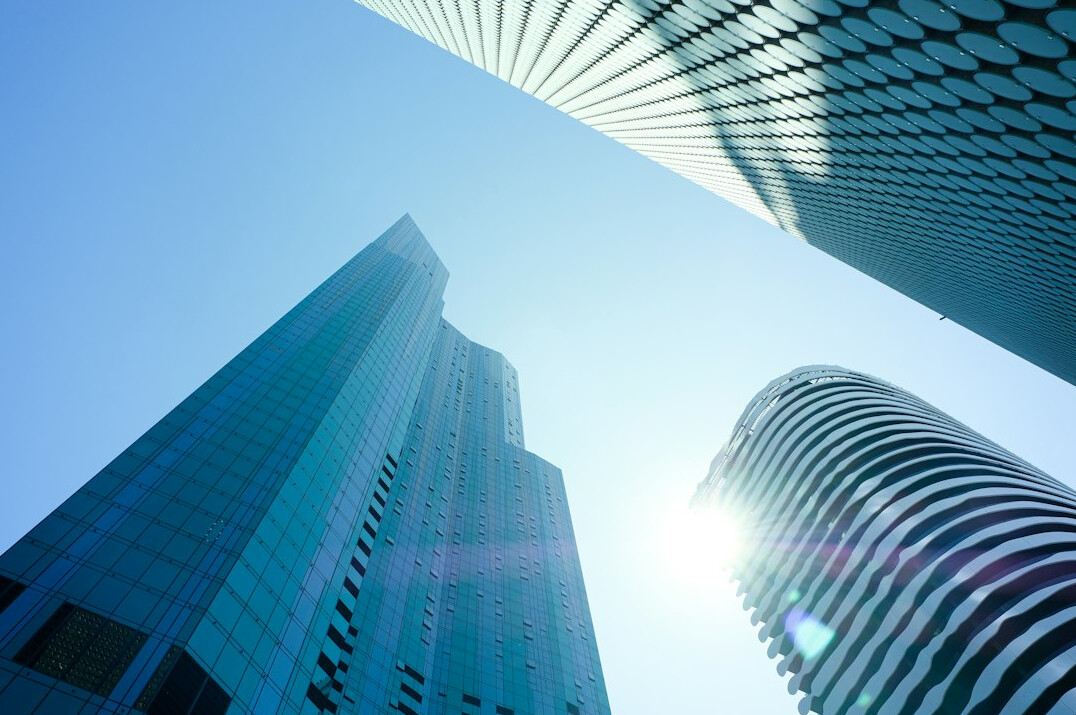 Glass office buildings seen from below against the sky